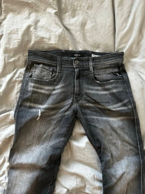 Replay Anbass jeans grå slitningar  - Oanvända snygga grå jeans från Replay, modell Anbass med slim fit. Jeansen har slitna detaljer, fem fickor och coola tvättade effekter. Nypris: 1899