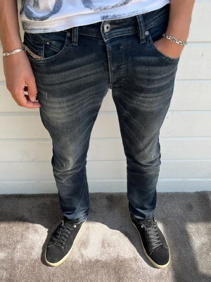 Diesel jeans mörkblå - Hej! Säljer mina personliga favoritjeans från alla jeans jag köpt denna gången! Perfekt passform, otrolig kvalitet, cool design med tvätt, knappgylf, småslitningar och detaljer överallt! Modellen på bilden är 183cm och väger 68kg som referens. Size: W30/L30, passform: ”Belther” Regular slim-tapered. 98% bomull 2% elastan. Hör av dig vid intresse!🙌