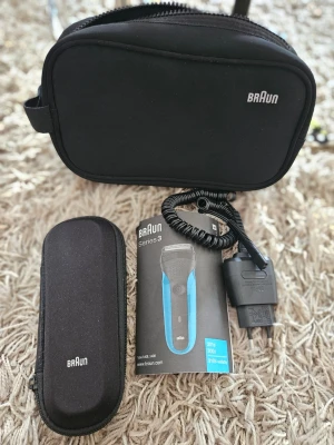 Braun Series 3 rakapparat med tillbehör - Elektrisk rakapparat Braun Series 3, modell 5408, i svart och blått. Medföljer laddare, originalfodral samt ett extra fodral och instruktionsbok. Perfekt för smidig rakning och enkel att ta med på resan.