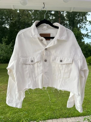 Vit croppad baggy jeansjacka, storlek S - En croppad/avklippt jeansjacka i crémevit färg. Sparsamt använd. Lite stel i materialet då den är nytvättad.   Passform: Baggy & cropped.  Brister: Några små prickar här och där.  Fickdetaljer: Två bröstfickor, inga sidfickor.  Säljanledning: Kommer ej till användning. 
