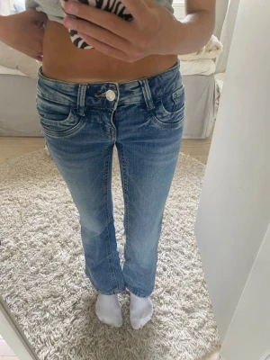 Blå lågmidjade bootcut jeans - Säljer ett par blå bootcut jeans som liknar Ltb jeans! Jeansen har låg midja, klassiska fem fickor och stängs med knapp och dragkedja. Perfekta för en avslappnad och trendig look.