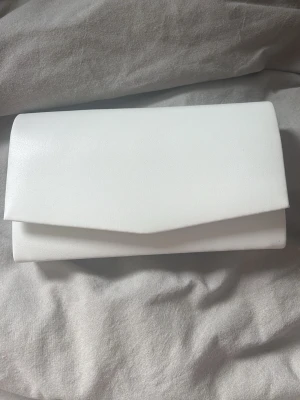 Vit liten balväska - En söt liten väska som jag använt på min bal. Endast använd en gång. Smidig att ha med sig och är ändå rymlig för dens storlek, har en liten ficka. Om jag minns rätt köpte jag den från boohoo.