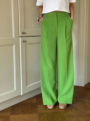 Gröna vida kostymbyxor från zara  - Stilrena kostymbyxor i en fräsch grön färg med hög midja och vida ben. Byxorna har pressveck framtill, hällor för skärp och sidfickor. Perfekta för en trendig och avslappnad look. Storlek XS!