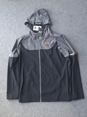 Helt ny under armour jacka med tags - Helt ny oanvänt undet armour windbreaker svart grå och röd logo passar folk som är 175-185