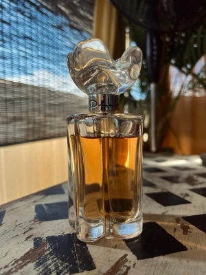 Oscar de la Renta Esprit; 100ml - Elegant parfymflaska från Oscar de la Renta med en unik, konstnärlig kork i transparent glas. Flaskan är genomskinlig och har en varm bärnstensfärgad vätska inuti. Perfekt som en lyxig detalj på sminkbordet. Cirka 85% kvar