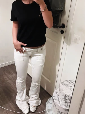 Vita bootcut jeans med broderade fickor - Snygga vita bootcut jeans med broderade detaljer på bakfickorna. Jeansen har låg midja, utsvängda ben och dekorativa sömmar. Perfekta för dig som vill sticka ut med en unik och fräsch stil. Helt nya, använd 1 gång bara!!!!