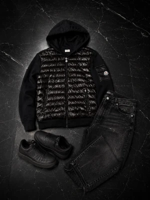 Svart cardigan med huva från Moncler - Snygg svart cardigan från Moncler med glansig, quiltad front och mjuka ärmar. Jackan har huva, dragkedja och en patch med Moncler-logga på ärmen. Perfekt för kalla vinterdagar och riktigt stilren look. Säljs då den aldrig kommit till användning! 