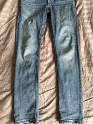 Ljusblå raka jeans - Säljer ett par ljusblå jeans med raka ben och klassisk femficksdesign. Jeansen har en snygg tvätt med lätt slitning på framsidan och bakfickor utan dekorationer. Perfekta till en avslappnad stil och passar till det mesta.