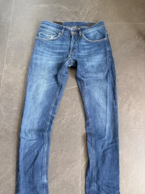 Dondup george jeans - Snygga blå slim fit jeans från Dondup med klassisk femficksmodell och orangea sömmar. Jeansen har en lätt tvättad look och normal midja. Perfekta för en avslappnad och trendig stil.