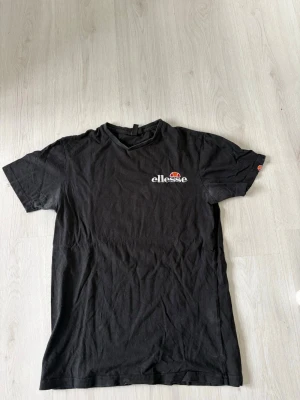 Svart t-shirt från Ellesse - Säljer en svart t-shirt från Ellesse med logga på bröstet. Klassisk passform och rund hals. Tillverkad i 100% bomull vilket gör den mjuk och skön att bära. Perfekt till jeans eller shorts för en enkel och clean look.
