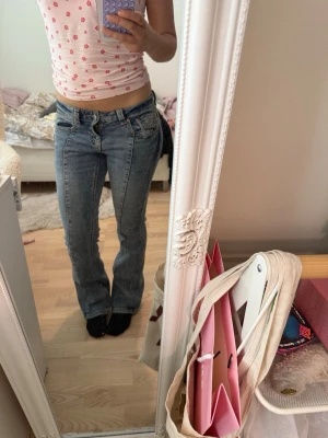 Blå low waist bootcut jeans - Säljer ett par blå low waist jeans med bootcut-modell och klassiska fem fickor. Jeansen har en snygg tvättad look och markerade sömmar. Perfekta för dig som gillar en avslappnad och trendig stil.