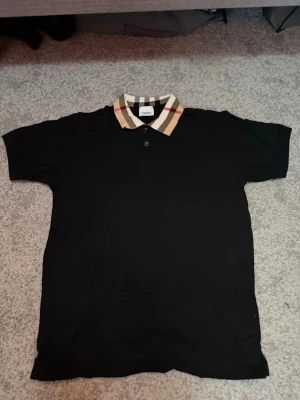 Burberry Piké Svart - Klassisk Burberry piké i svart med stilren design. Enkel att matcha och passar både till vardags och mer uppklädda outfits.  Färg: Svart Storlek: S  Fraktar inom 24h vid snabb affär. Byten är inte aktuella.  #Burberry #BurberryPolo #Piké #Menswear #LuxuryFashion