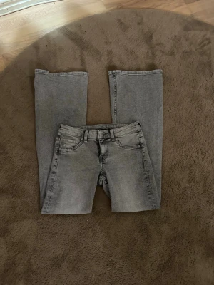 Gråa bootcut jeans med låg midja - Säljer ett par gråa bootcut jeans från hm med låg midja i storlek 36. Jeansen har inga tecken på användning 