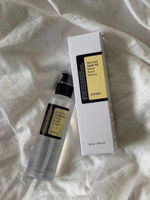 COSRX Advanced Snail 96 Mucin Essence - En genomskinlig toner i plastflaska från COSRX med svart pump och gul etikett. Produkten heter Advanced Snail 96 Mucin Power Essence och innehåller 100 ml. Förpackningen är stilren och modern, perfekt för dig som vill boosta din hudvårdsrutin .
