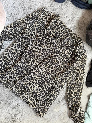 Leopardmönstrad blus från ONLY - Snygg leopardmönstrad blus från ONLY i transparent, lätt material. Blusen har långa ärmar och två snören vid halsen. Passar till både jeans och kjol för en trendig look med ett snyggt leopardmönster. Storlek xs men kunde likaväl varit en S. Endast använd ett fåtal gånger.