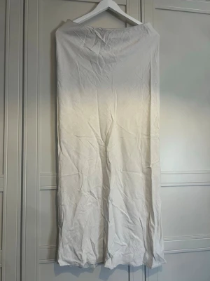 Vit långkjol i linne - Säljer en enkel och stilren vit långkjol i linne. Kjolen har en rak passform och är perfekt för dig som gillar minimalistisk stil. Passar till många olika looks och är superfräsch till sommaren.