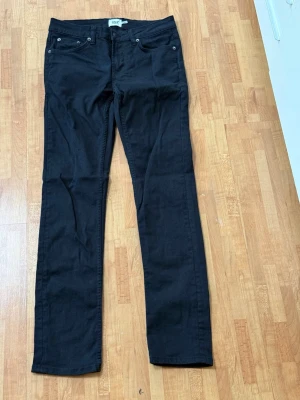 Svarta raka jeans - Säljer ett par svarta jeans med rak passform och klassisk femficksdesign. Jeansen har bälteshällor och silverfärgade nitar. Perfekta för dig som gillar en enkel och stilren look.