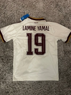 Spanien andraställ vm26 -  en vit Spanien andraställ tröja från Adidas med Lamine Yamal och nummer 19 på ryggen. Tröjan har 2 stjärnor ⭐️ på bröstet efter de vunnit vm. Tröjan är i storlek M och är helt ny. 