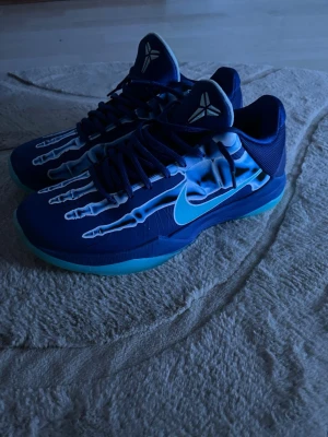 Blå sneakers med skelettmönster Nike - Ett par blåa basket skor, Kobe 5 xray. Köpte de från Nike. Har haft de runt 3-4 månader, har använt de ett par gånger, inga skador. Säljer de för att jag har börjat få skavsår, och de är lite tighta på mina fötter. De har jätte bra grepp
