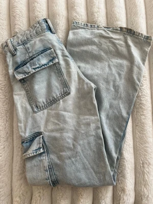 Ljusblå cargobyxor  - Säljer ett par ljusblå cargobyxor i denim med bred passform och stora fickor på sidorna. 