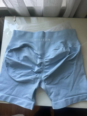Relode nya träningsshorts Aura - Helt nya träningsshorts ”Aura Seamless Scrunch Shorts - Light Blue” , strl M, ljusblå pastellfärg🩵 säljer då de är förstora för mig. Säljer en matchande halterneck top i strl S! Nypris: 579kr