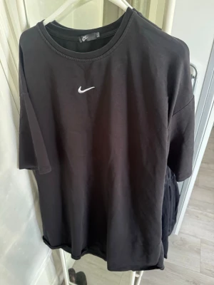 Svart Nike T-shirt  - Mysigt svart T-shirt från Nike med enkel design. Tröjan har rund halsringning och korta ärmar med fckor samt en liten vit Nike-logga på bröstet. 