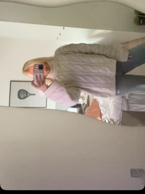 Vit kabelstickad polotröja - Säljer en vit kabelstickad polotröja med oversized passform och långa ärmar. Tröjan har hög polokrage och ett klassiskt flätmönster som ger en mysig och trendig look. Perfekt att styla med jeans eller kjol för en chill outfit.