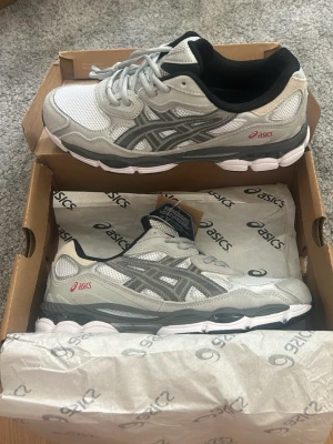 Asics grå och vita sneakers - Feta Asics i en skön färg som passar till allt. Skorna är i storlek 43.5. De är endast provade så helt nya. Pris kan alltid diskuteras vid snabb affär. 