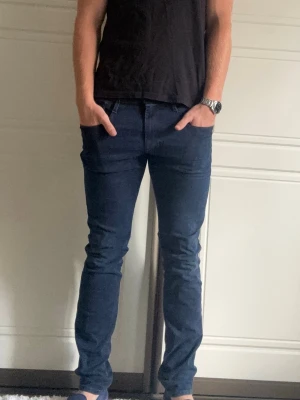 Replay Anbass - REPLAY ANBASS  Storlek: W31 L34  Passform: Slim fit  Använding: Jeansen är i bra skick utan defekter  Modellen på bilden: 185CM och väger 80KG