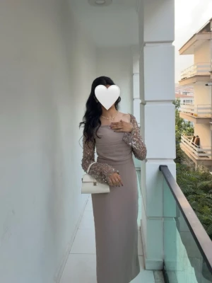Klänning fest/bal - Elegant beige aktig långklänning med långa, transparenta spetsärmar dekorerade med blommiga detaljer. Klänningen har en figurnära passform och en stilren, rak siluett. Perfekt för speciella tillfällen när du vill känna dig extra fin. Hade denna på ett bröllop, den funkar även bra för middag, bal, eller speciella tillfällen. Inbyggd bh i toppen. Klänning sälja endast via meddelanden, gärna om man kan komma och hämta den, går då att sänka pris. ☺️