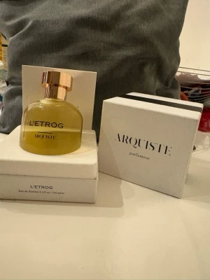 L'Etrog parfym från Arquiste - L'Etrog från Arquiste är en exklusiv Eau de Parfum i en rund glasflaska med gul vätska och elegant guldfärgat lock. Flaskan kommer i en stilren vit förpackning med svart text. Volymen är 100 ml. Mörka flaskan för män. Och ljusa flskan för kvinnor 