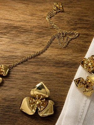 Guldigt smyckeset med blomdetaljer - Unikt smyckeset i guld med halsband och örhängen. Blommiga hängen med tre blad och små kulor i mitten ger en elegant och trendig look. Perfekt för dig som vill sticka ut med accessoarer i metallisk finish.