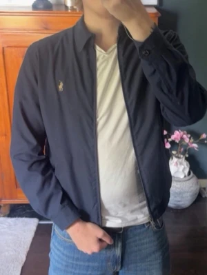 Ralph Lauren jacka - Säljer denna riktigt snygga Polo Ralph Lauren-jacka i marinblått, som är i toppskick, 9/10. Jackan har använts max 10 gånger och är väldigt väl omhändertagen.  Jackan köptes för ungefär 2 år sedan, när jag vägde betydligt mindre och vanligtvis använde XS/S i kläder. Kan användas uppknäppt om man har storlek M🌟🤝