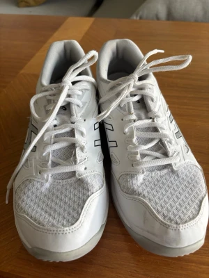 Vita Asics Gel-Rocket 11 sneakers - Säljer ett par vita Asics Gel-Rocket 11 sneakers med svarta detaljer i stl 40. Skorna har mesh-överdel för bra ventilation och klassisk snörning. Perfekta för inomhussport eller gym. Snygg och sportig design med Asics-logga på sidan. Skicka för mer information!😊