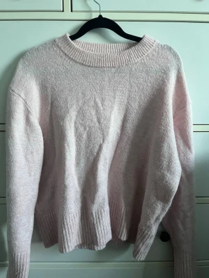 Ljusrosa stickad tröja - Mysig ljusrosa stickad tröja med rund halsringning och ribbade muddar vid ärmslut och nederkant. Tröjan har en avslappnad passform och är perfekt för kyligare dagar. ❣️