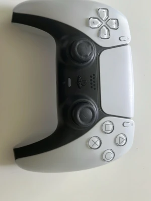 Vit och svart PS5 DualSense handkontroll - Säljer en snygg vit och svart DualSense handkontroll till PlayStation 5. Kontrollern har ergonomisk form, två analoga spakar, touchpad och klassiska PlayStation-knappar. Tillverkad i plast med matt finish och modern design. Har stickdrift men går alltid att fixa