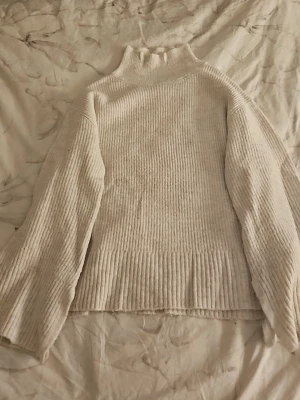 Beige ribbstickad polotröja 157 - Mysig beige ribbstickad polotröja från 157 i storlek XS. Tröjan har hög krage, långa ärmar och en avslappnad passform. Perfekt för kalla dagar och enkel att matcha med olika outfits.