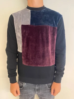 Färgglad velourtröja från La Vichy - Cool långärmad tröja från La Vichy i velour med stora block i vinrött, marinblått och grått framtill. Tröjan har svart bas och rund halsringning, perfekt för dig som gillar unika plagg med mjuk känsla.