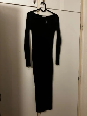 Svart ribbad långklänning från Zara - Snygg svart långklänning från Zara med ribbad struktur och lång ärm. Klänningen har en rundad halsringning och sitter figurnära för en stilren look. Perfekt för dig som gillar minimalistisk och trendig stil.