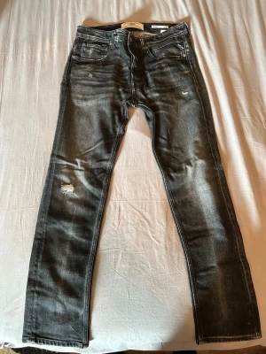 Svarta slitna jeans med raka ben - Säljer ett par feta Replay GROVER jeans. Snygga slitdetaljer på låret och vid fickorna. Perfekta för en avslappnad och trendig look. Nyskick. Storlek w32/l30 🤩