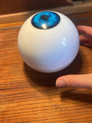 Magic 8-ball med blått öga - Cool Magic 8-ball i form av ett stort vitt klot med ett blått öga på ovansidan. Perfekt för att ställa frågor och få slumpmässiga svar. Tillverkad i plast och har ett fönster på undersidan där svaret visas.