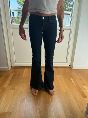 Mörkblå bootcut jeans - Snygga mörkblå jeans med bootcut passform och klassisk femficksdesign. Jeansen har hög midja och är tillverkade i ett stretchigt denimtyg som sitter bekvämt. Perfekta för dig som gillar en tidlös och trendig look.