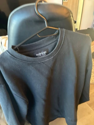 Svart sweatshirt från Sams Basic - En enkel svart sweatshirt från Sams Basic i storlek XS. Tröjan har rund halsringning och ribbade muddar vid ärmslut och nederkant. Perfekt för en avslappnad och stilren look.