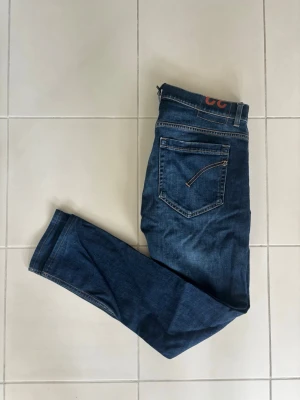 Jeans Dondup  - Oerhört feta jeans från Dondup i mörkblåfärg med riktigt snygga och eleganta detaljer. Modellen är Dondup George! Detta är jeans som passar till allt året om. Otroligt fräscha och stilrena jeans! Längd - 97 cm och bredd - 45 cm 