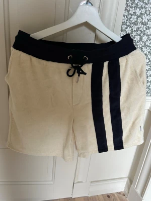 Beiga frottéshorts från Les Deux - Snygga beiga shorts från Les Deux i mjuk frotté med bred svart midjeresår och snörning. Stl S men passar ännu bättre M. Endast testade. 