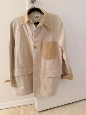 Beige overshirt/jacka från Zara -  beige overshirt/jeansjacka från Zara med ljusbruna detaljer på krage, bröstficka och ärmslut🤎 perfekt inför hösten! 