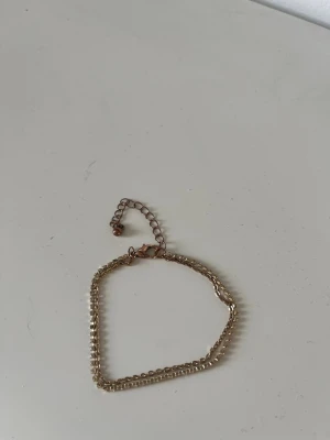 Tunt guldigt kedjearmband - Snyggt och enkelt armband i guldton med tunn kedja och justerbar längd. Armbandet har två olika kedjor som sitter tillsammans i ett.