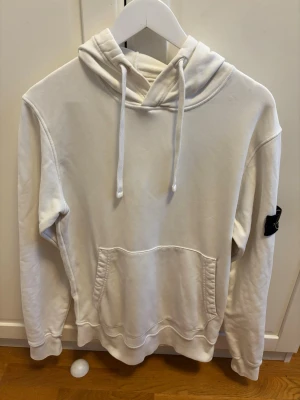 Vit hoodie från Stone Island - En riktig schysst Stone Island hoodie i vit färg, i storlek M. Självklart äkta köpt på Jupiter för nåt år sen men använd fåtal gånger.Är öppen för prisförslag så bara att skriva för att diskutera pris pytte liten fläck finns men inget som syns vid användning!