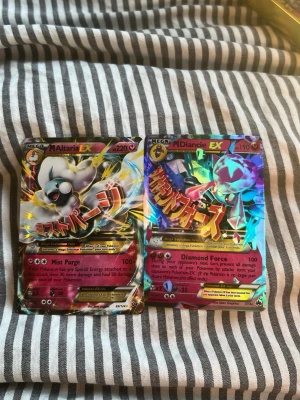 Pokémonkort Mega Altaria & Diancie EX - Två Pokémonkort: Mega Altaria EX och Mega Diancie EX. Båda korten har färgstarka holografiska motiv med japansk text och coola effekter. Perfekt för samlare eller dig som vill boosta din kortlek med unika och kraftfulla kort.