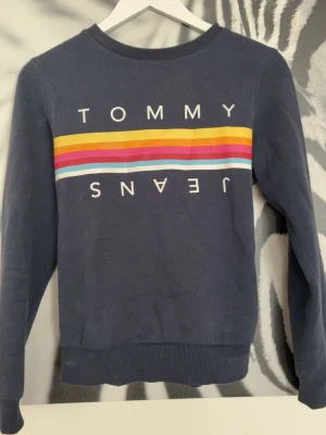 Blå sweatshirt Tommy Jeans - jätte snygg sweatshirt ifrån tommy jeans, lite urtvättad då den är köpt för väldigt länge sen men generellt tycker jag de bara är snyggt. Postar samma dag!